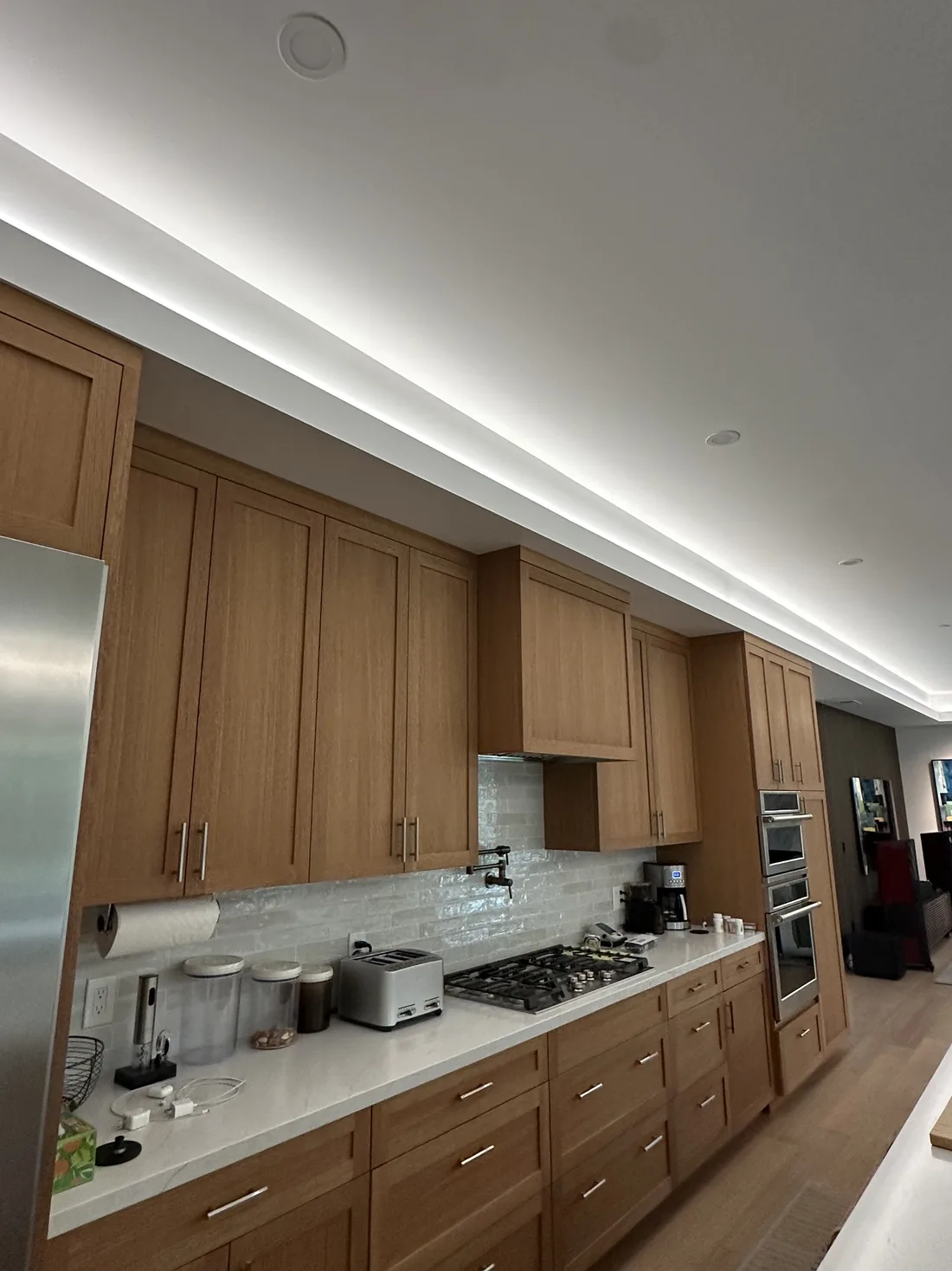 White-oak kitchen with a continuous LED cove light run washing the ceiling alongside recessed downlights, in Sonoma County, California