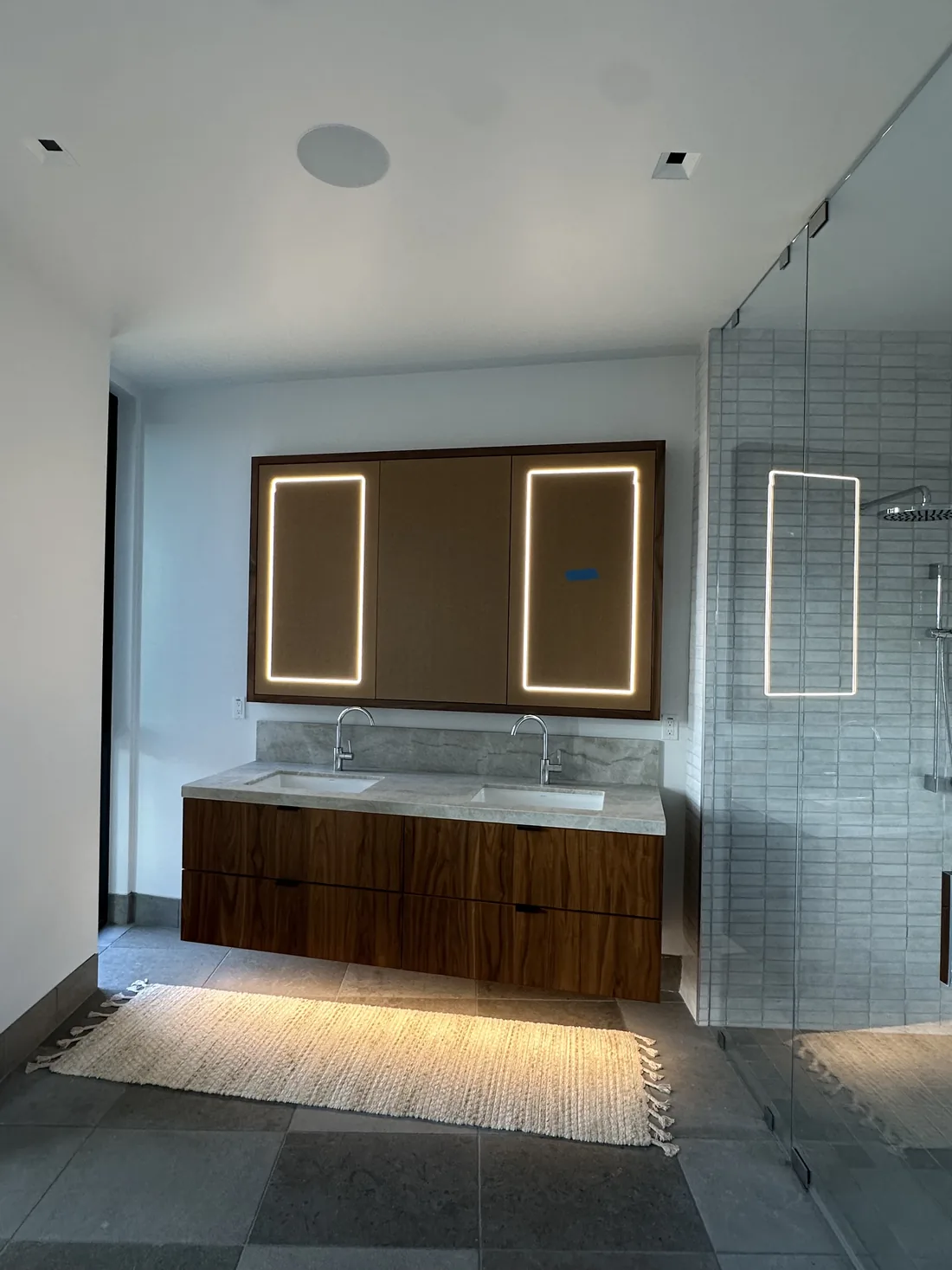 Backlit mirrors and toe-kick accent lighting under a floating vanity in a Sonoma County bathroom